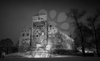 Black and white photo of Turku Castle at night, it is a medieval building in the city of Turku in Finland. It was founded in the late 13th century and stands on the banks of the Aura River