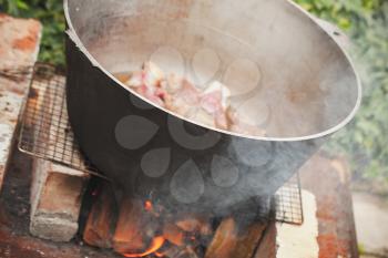 Lamb with sliced vegetables boiling in a cauldron. Outdoor preparing of Chorba soup