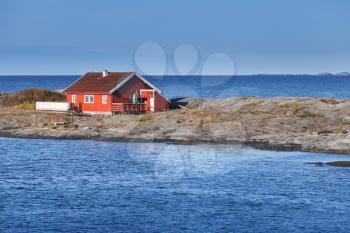 Rural Norwegian landscape, traditional red wooden house on rocky island. Norway, Trondheim district