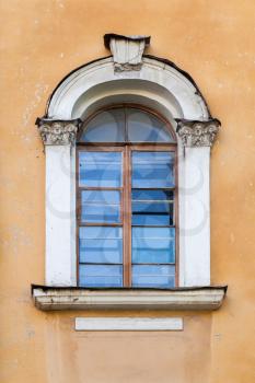 Classical window with arch and decorative sculptures  in yellow stone wall. Saint-Petersburg, Russia. Background photo texture