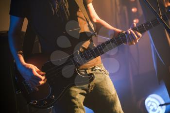 Rock music theme, bass guitar player, close-up photo with soft selective focus