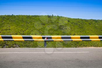 Striped yellow black traffic barrier on the side of mountain road in Portugal