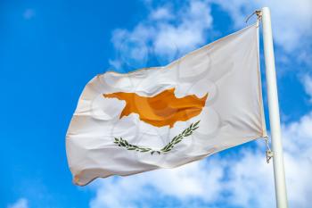 National flag of Cyprus waving on a flagpole over cloudy blue sky