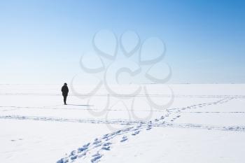 Footsteps of lonely girl walking on frozen sea covered with snow. Russian winter