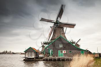 Old wooden windmill on Zaan river coast, Zaanse Schans town, popular tourist attractions of the Netherlands. Suburb of Amsterdam