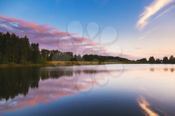 Colorful clouds over still lake in evening, natural background photo. Dramatic landscape