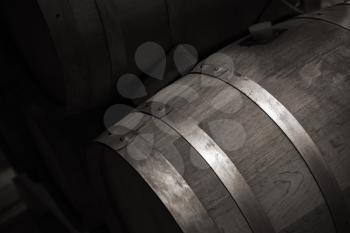 Wooden barrel with red wine in dark winery, close up monochrome photo with selective focus