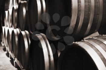 Wooden barrels in winery, close up monochrome photo with selective focus
