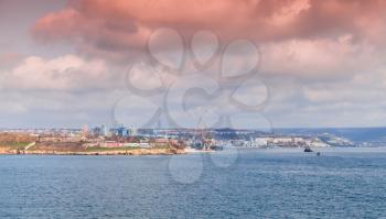 Sevastopol Bay, coastal cityscape with cranes and ships under cloudy sky