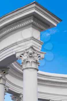 Classical round portico vertical fragment, white columns under blue sky