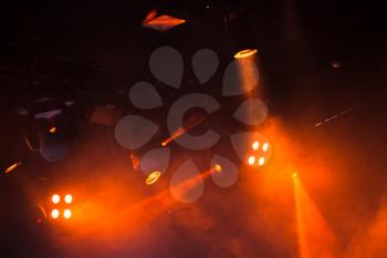 Red lights with strong beams in smoke over dark background, modern stage illumination equipment
