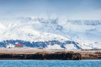 Coastal Icelandic landscape with snowy mountains and lonely house. Reykjavik, Iceland