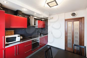 Modern kitchen room interior. Black, red and white design, wooden door