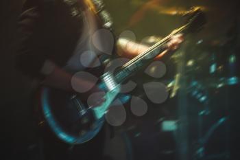 Rock and roll live music background, blurred electric guitar player on a stage, motion blur effect