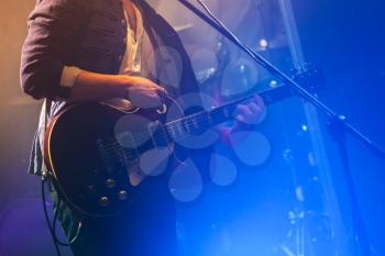 Guitarist on stage plays on electric guitar, photo with soft selective focus