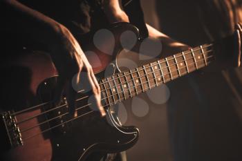 Guitarist plays on of bass guitar, soft selective focus, live music theme