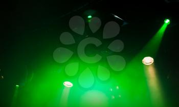 Green scenic spot lights, beams and smoke over dark background, modern stage illumination