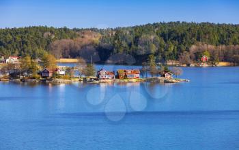 Rural Swedish landscape with coastal villages. Traditional colorful wooden houses and barns on islands in sunny summer day