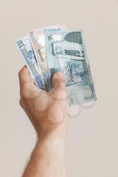 Male hand with Jordanian dinars banknotes over gray background, vertical photo