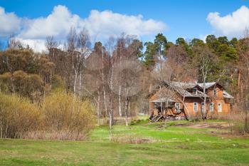 Russian rural landscape with old wooden house near spring forest