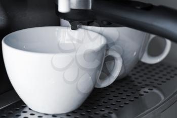 Empty white ceramic cups in espresso coffee machine.