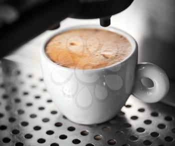 White ceramic cup of fresh espresso with foam in the coffee machine