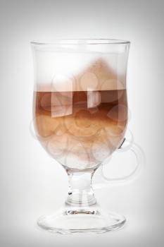 Glass mug with handle of latte coffee, closeup studio photo