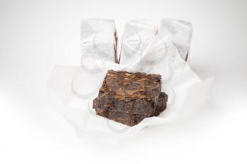 Small pressing briquette of black Chinese Shu Pu-erh tea on white background