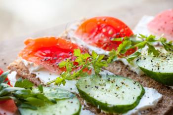 Healthy food theme. Sandwiches made of Finnish rye crisp bread, soft cheese, cucumber, tomato, parsley and black pepper