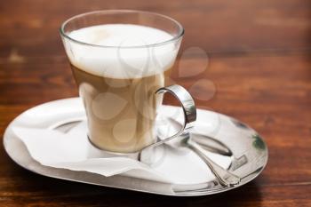 Cappuccino. Cup of coffee with milk foam stands on wooden table in cafeteria