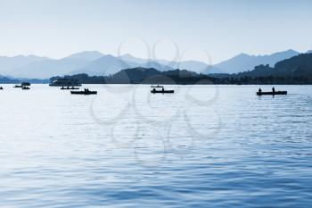West Lake, panorama with local ordinary people in floating boats, Hangzhou city, China. Blue toned monochrome photo