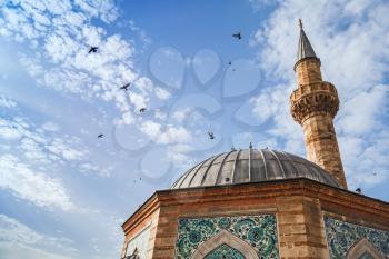 Doves fly over Ancient Camii mosque. Konak square, Izmir, Turkey