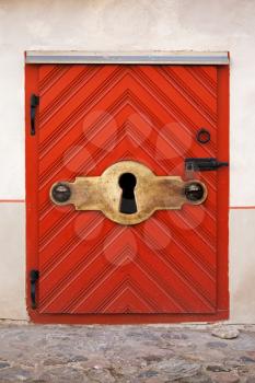 Old red wooden door with lock and large keyhole, old fashioned safety concept