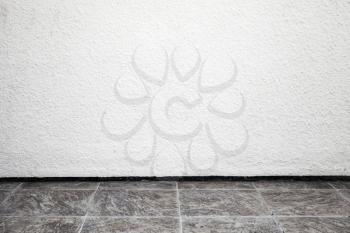 White interior background with rough stucco wall and tiling floor