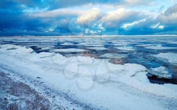 Winter coastal landscape with floating ice fragments on sea water. Gulf of Finland, Russia