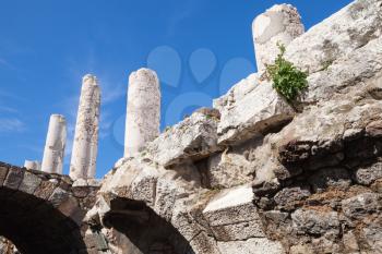 Ancient white columns and arches over blue sky background, fragment of ruined roman temple in Smyrna. Izmir, Turkey
