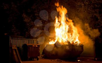 Fire in the city night: burning trash container