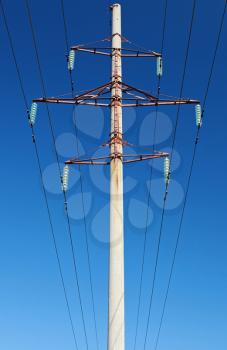 High voltage power lines and pylon above clear blue sky