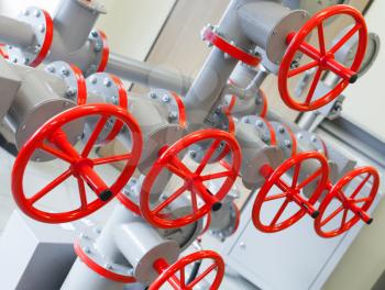 Group of red industrial valves on gray pipelines system