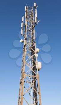 Communication radio tower with devices above blue sky