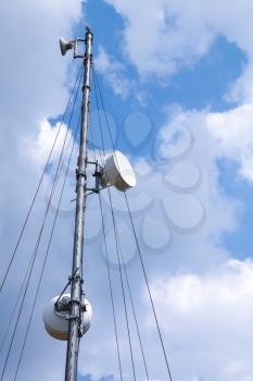 Communication radio tower with devices above blue sky background