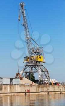 Big industrial harbor crane works on the river coast in Bulgarian port