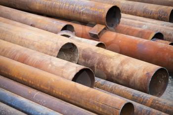 Pile of rusted industrial steel pipes lay on the ground