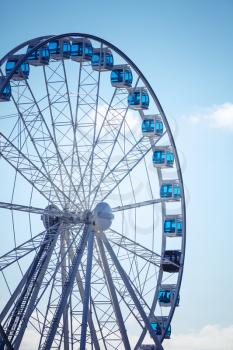 Ferris wheel above blue sky background. Vertical photo