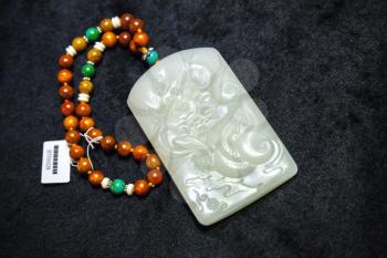 Hangzhou, China - December 2, 2014: Traditional Chinese stone amulet made of jade with dragon art carving lays on counter in gemstones shop