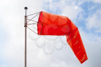 Windsock. Red wind indicator over blue cloudy sky