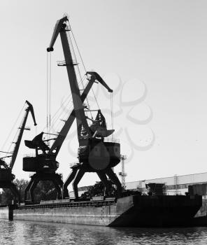 Dark silhouettes of industrial port cranes, Danube River, Bulgaria. Black and white photo