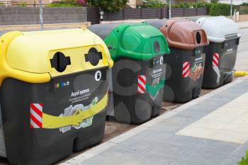 Calafell, Spain - August 22, 2014: Colorful plastic containers in a row for separate garbage collection
