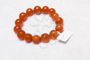 Chinese bracelet made of red round agate stones lays on white counter