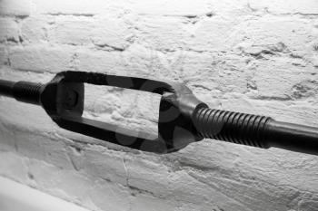 Old black turnbuckle, close up photo over white brick wall background